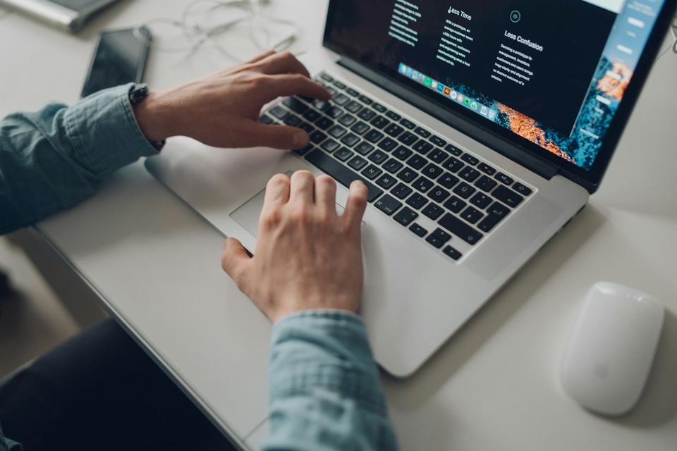 Hands typing on a laptop showing a website